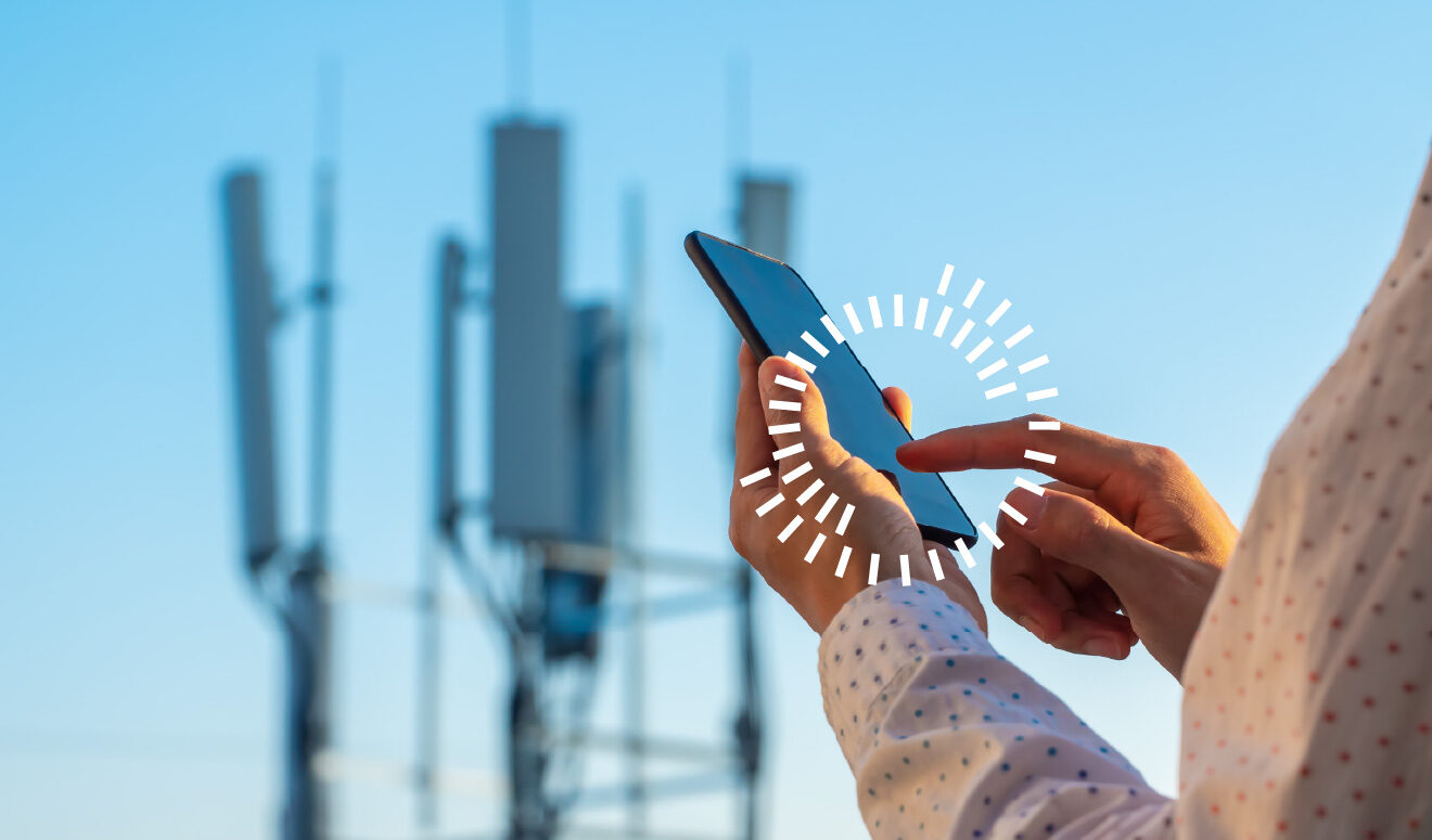 a person with a cell phone with a cell tower in the background