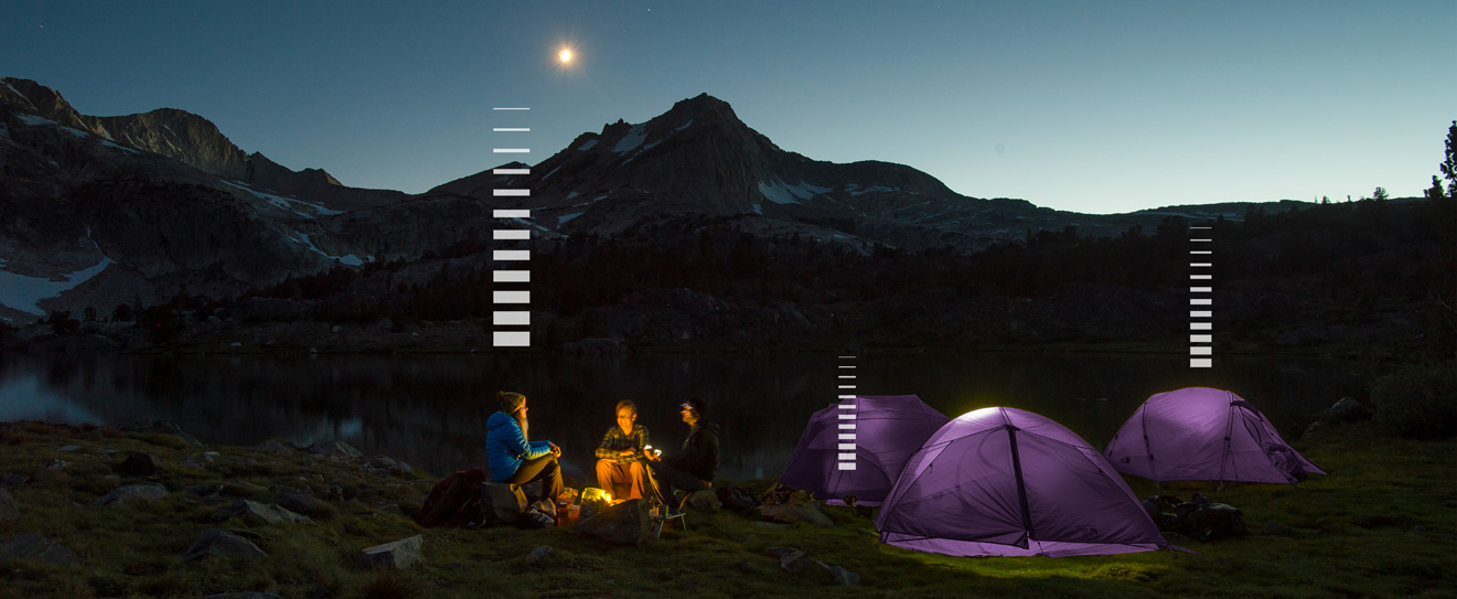 3 campers around a campfire with purple tents